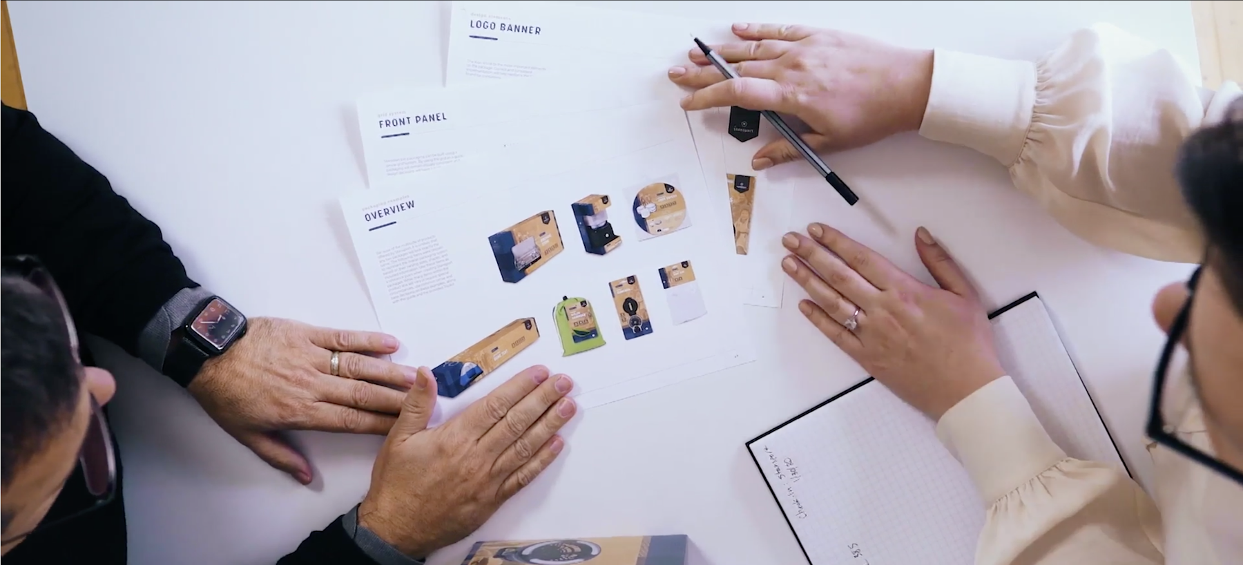 Capsule packaging concepts printed on table with designers reviewing.