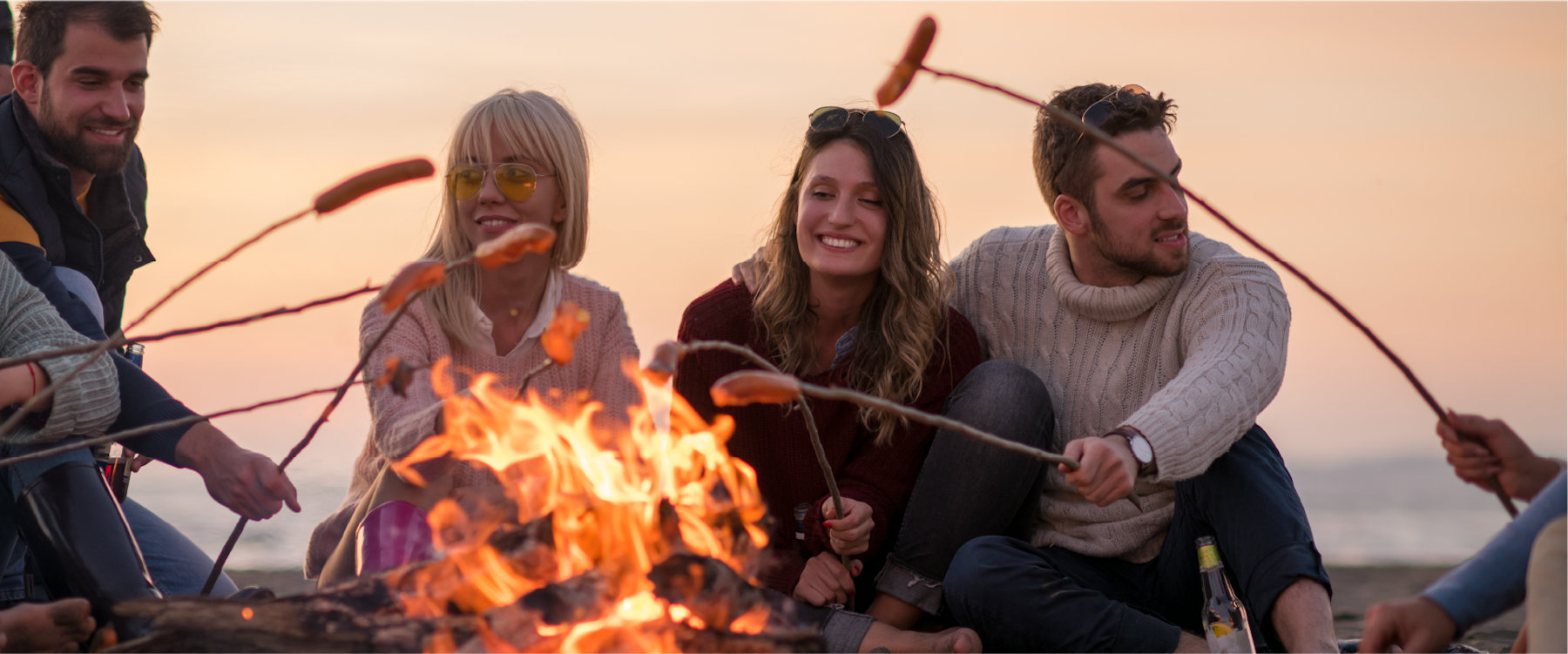 A campfire beach scene with four people cooking hotdogs for Endless Coast brand design.