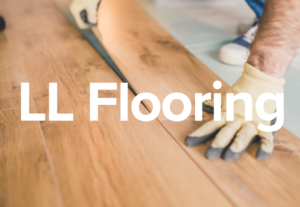 The LL Flooring brand name words on a wood floor being installed by hands.