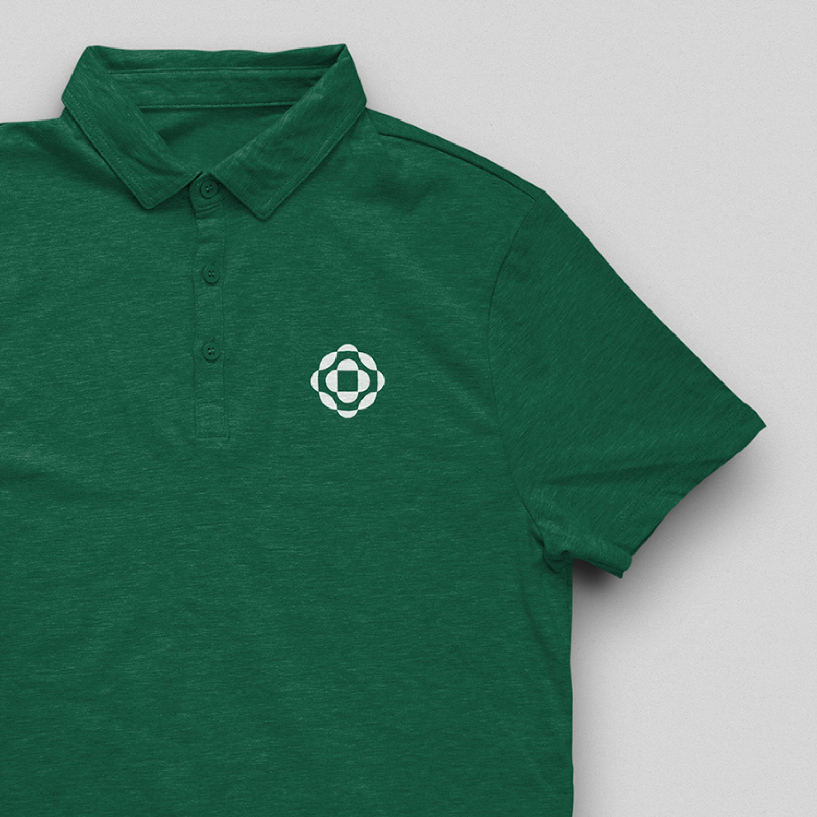 Stratasight t-shirt: An example of the white Stratasight logo mark, developed by Capsule in Stratasight's 2026 rebrand, printed on a green polo t-shirt.