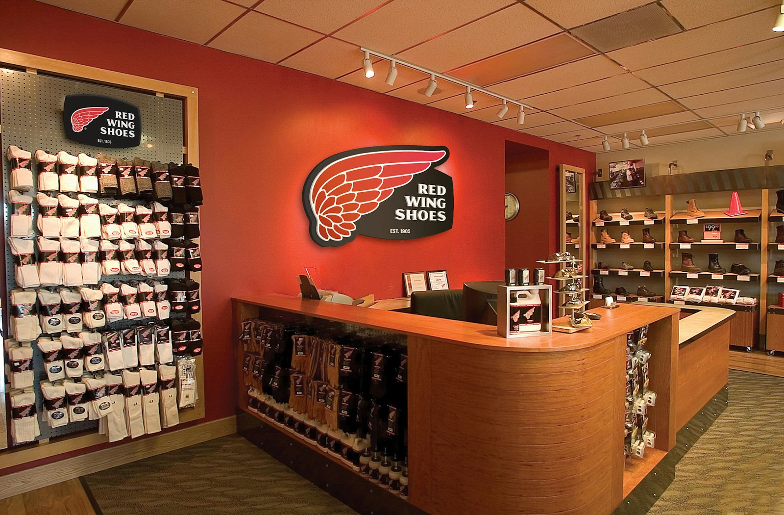 The Red Wing Shoes brand design logo behind retail checkout desk on large sign.