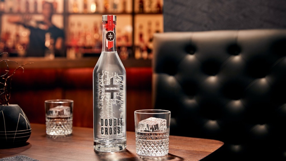 A Double Cross Vodka brand bottle design and glass on a bar table.