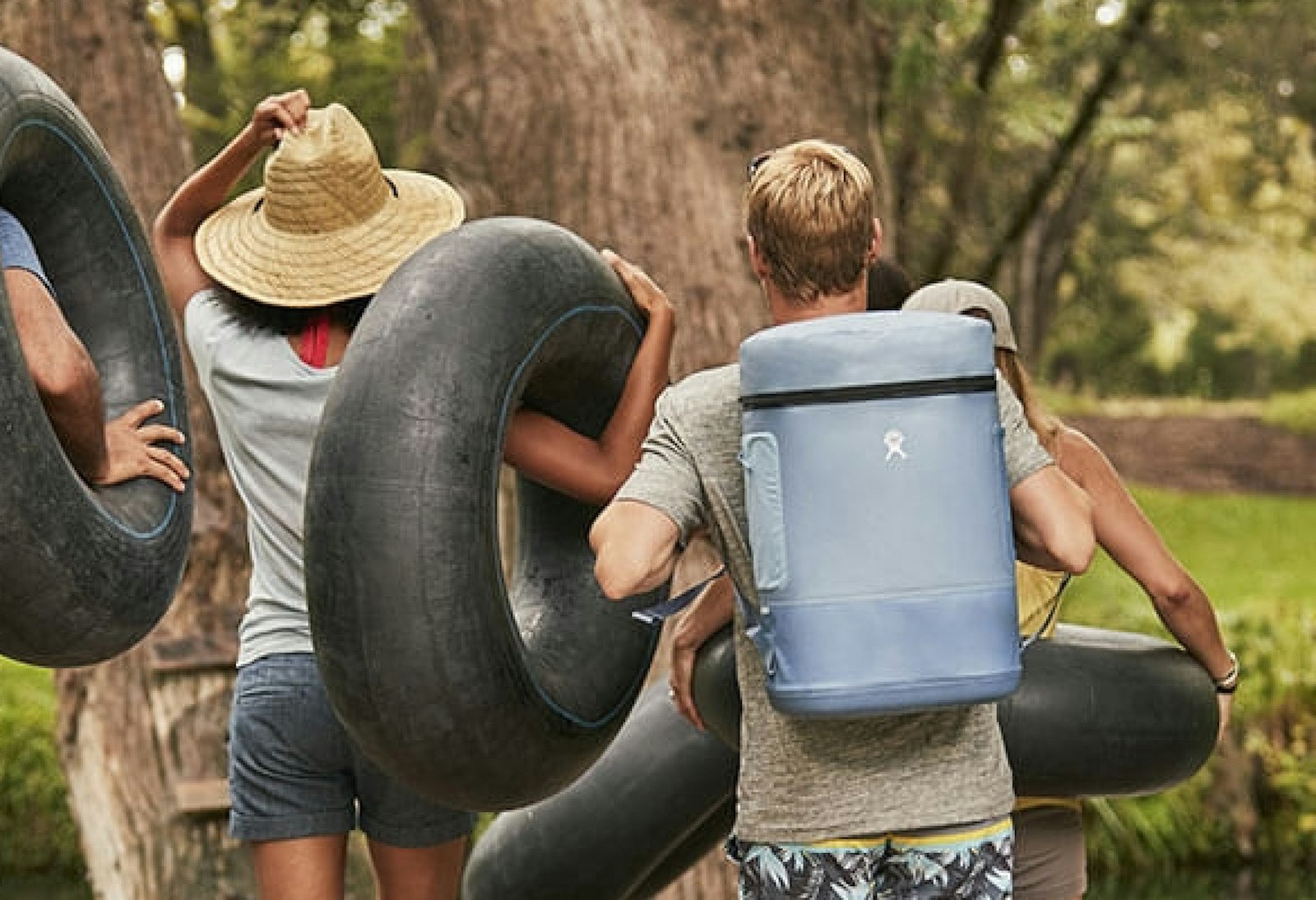 The Hydro Flask brand design backpack cooler worn by hiker carrying a tire tube.