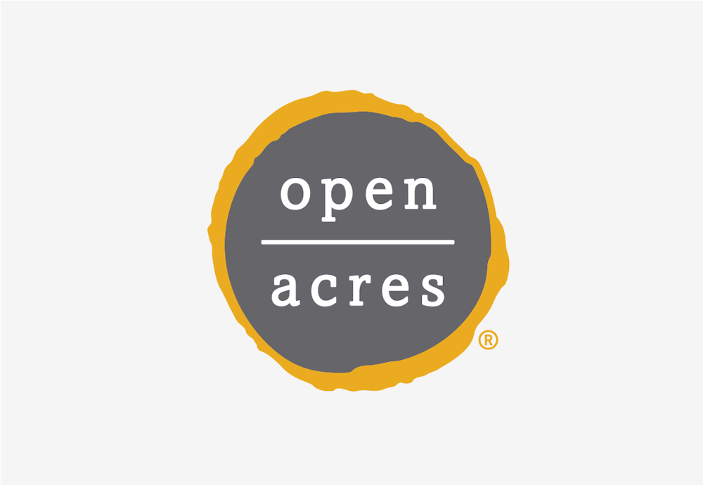 The Open Acres brand logo design with white type on grey and yellow circle background.