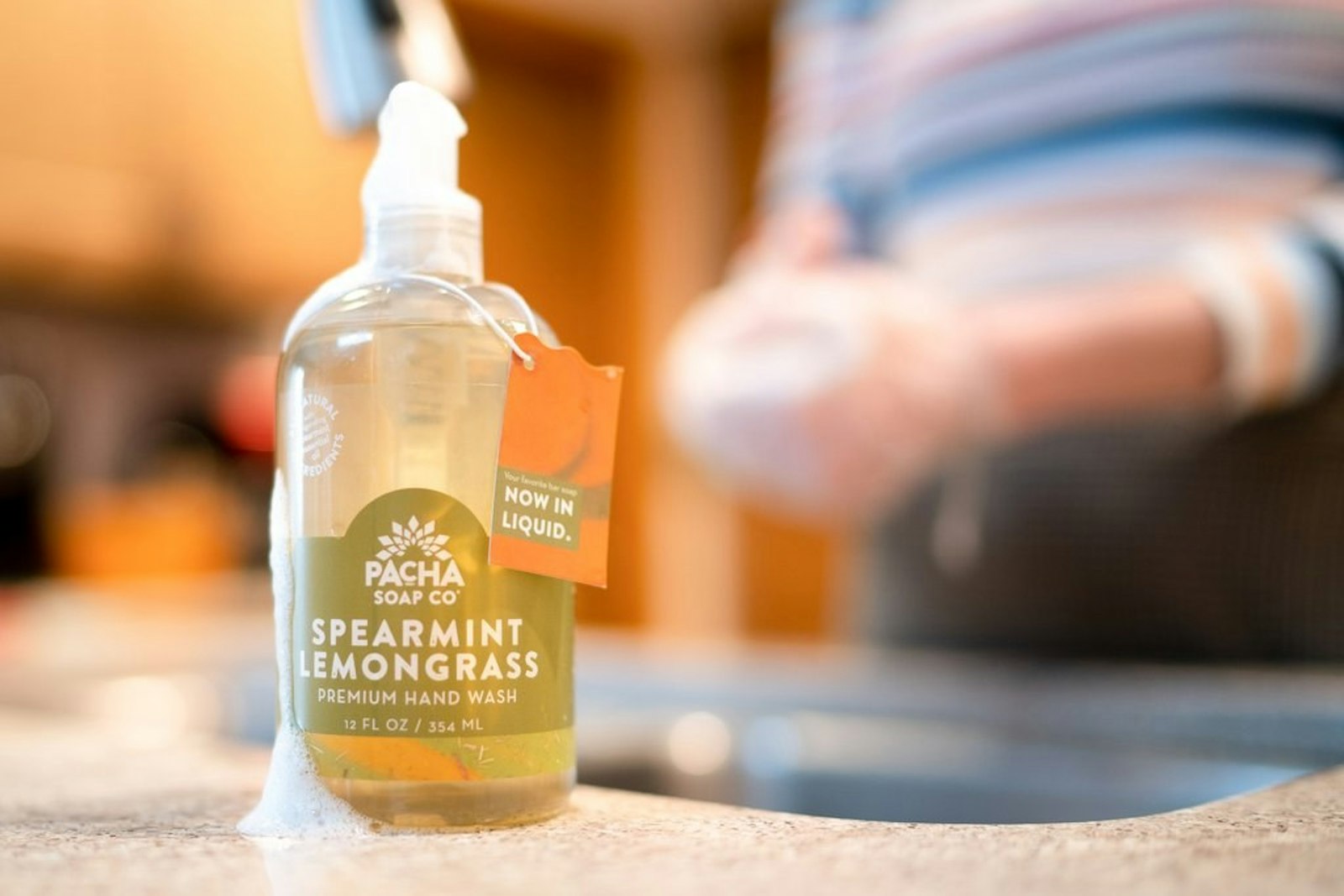 The Pacha Soap brand packaging design in liquid package on countertop with people behind.