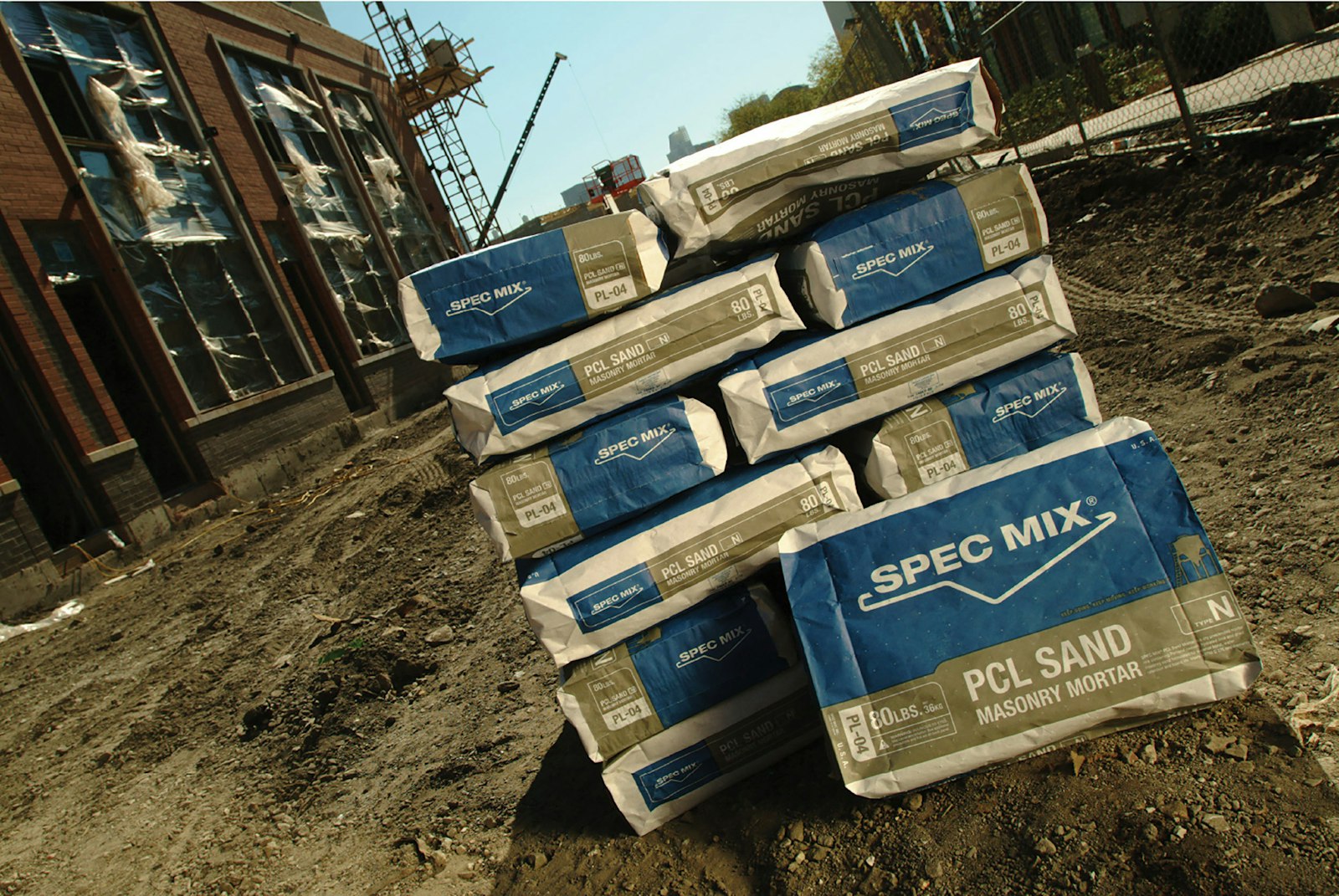 Spec Mix packaging and logo design on concrete product bags stacked in middle of construction.