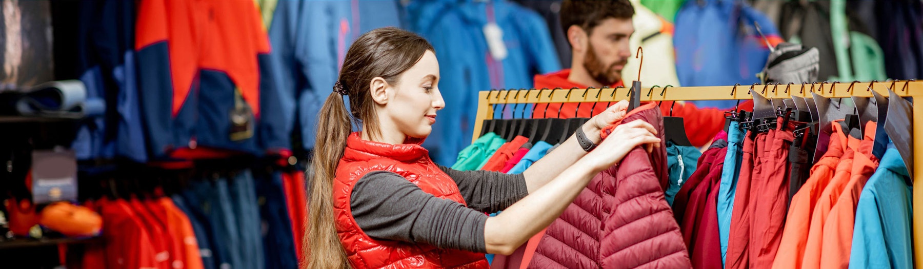 A woman shopping in retail for Patagonia jacket in retail display.