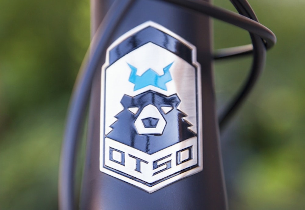 The OTSO bike brand logo design with bear with crown on a bike.